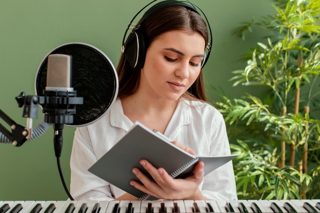 Musicista femminile che suona la tastiera del pianoforte e scrive canzoni durante la registrazione