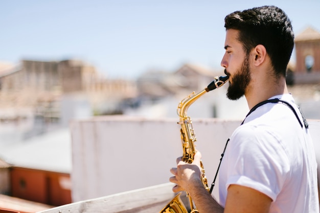 Musicista lateralmente che suona il sassofono