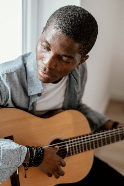 Musicista maschio a suonare la chitarra sul letto