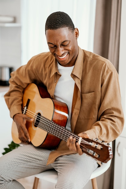 Musicista maschio di smiley a casa a suonare la chitarra