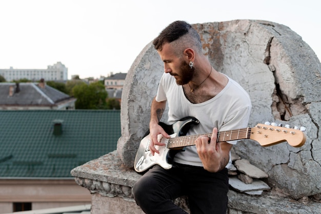 Musicista maschio sul tetto a suonare la chitarra elettrica