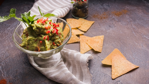 Nachos vicino guacamole in ciotola di vetro e tovagliolo