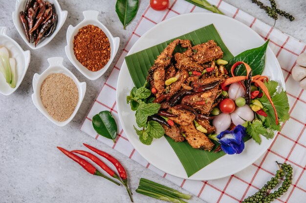 Nam Tok di maiale con peperoncino fritto, pomodoro, lime, cetriolo e pepe fresco. Cibo thailandese.