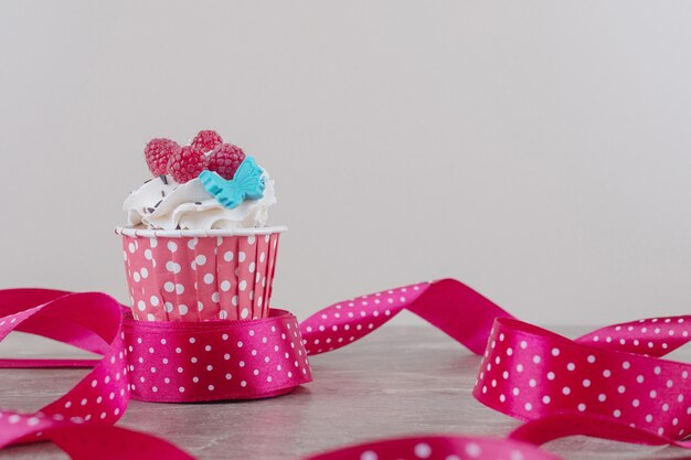 Nastri intorno a un cupcake ricoperto di crema su marmo