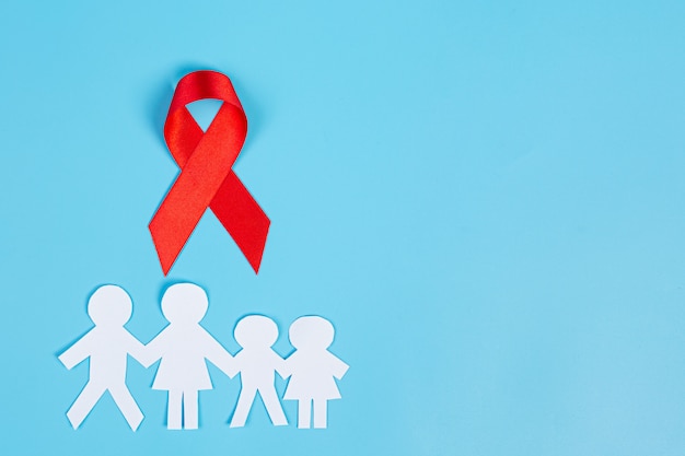 Nastro rosso di conoscenza e carta tagliata in famiglia, consapevolezza dell'HIV, Giornata mondiale contro l'AIDS e Giornata mondiale della salute sessuale.