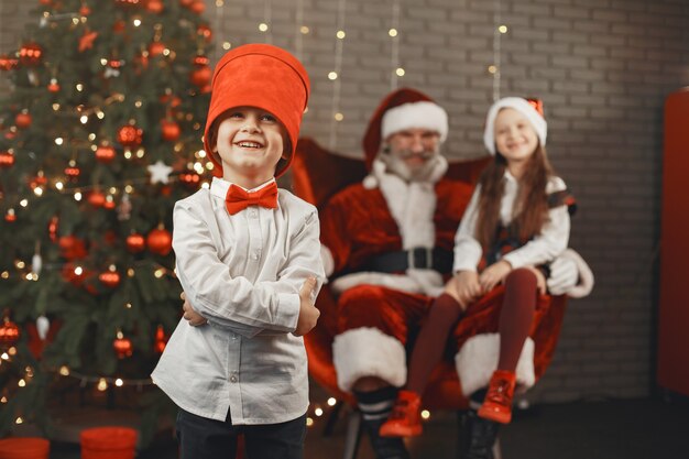 Natale, bambini e regali. Babbo Natale ha portato regali ai bambini. Bambini allegri con doni che abbracciano Babbo Natale.