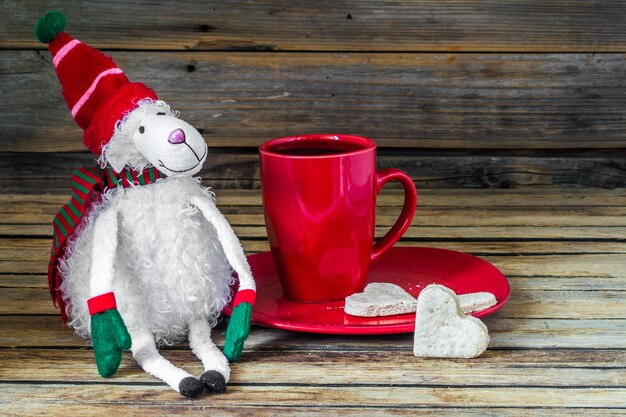 Natale, tazza rossa con caffè e dessert sulla tavola di legno