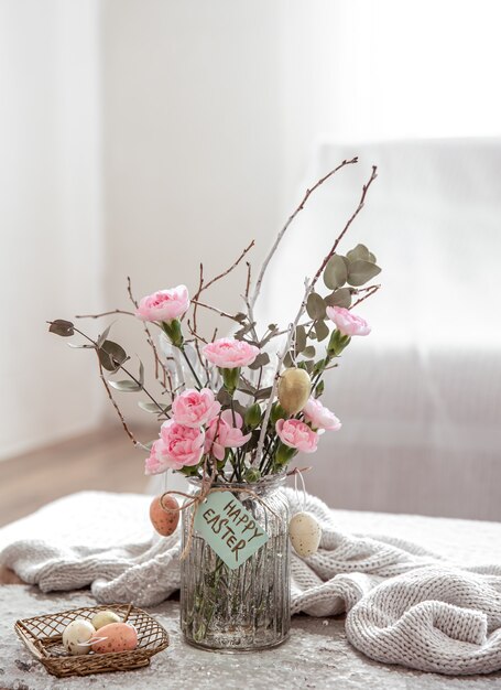Natura morta con fiori freschi in un vaso e dettagli di decorazioni festive di Pasqua su uno sfondo sfocato