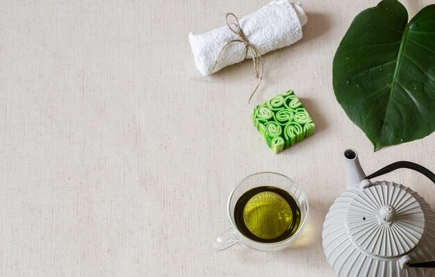 Natura morta con sapone, asciugamano, foglia e spazio copia tè verde. Concetto di salute e bellezza.