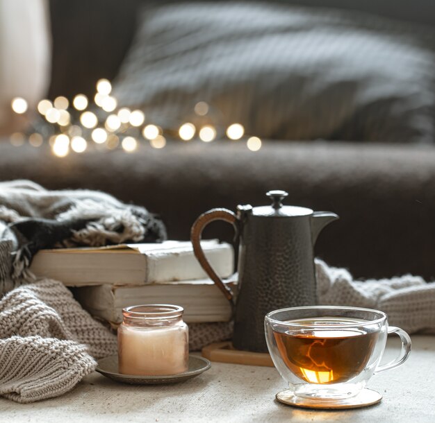 Natura morta con una tazza di tè, una teiera, libri e una candela in un candeliere
