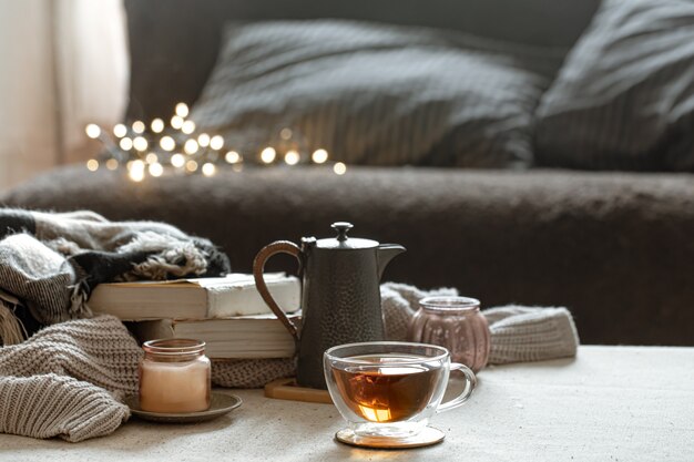 Natura morta con una tazza di tè, una teiera, libri e una candela in un candeliere