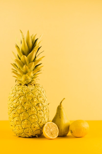 Natura morta di ananas; limone e pere su sfondo giallo
