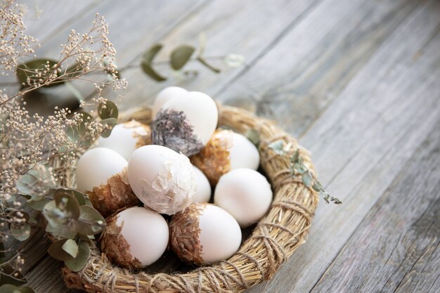 Natura morta di Pasqua con uova di Pasqua decorate e nido decorativo su una superficie di legno con ramoscelli asciutti