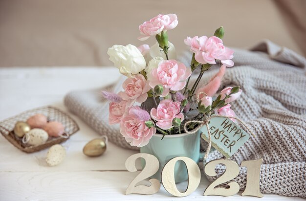 Natura morta pasquale con fiori freschi di primavera in un vaso, lavorata a maglia con un elemento e numero decorativo dell'anno 2021.