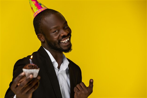 Negro carino felice sorridendo alla telecamera e in possesso di una torta di compleanno