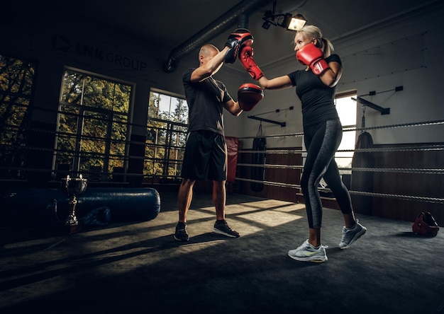 Nella palestra buia sul ring l'allenatore esperto e la giovane donna hanno una lotta di kick boxing.