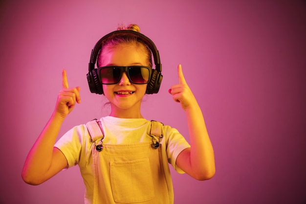 Neon ritratto di giovane ragazza con le cuffie che gode della musica. Stile di vita dei giovani, emozioni umane, infanzia, concetto di felicità.