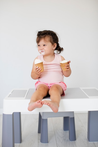 Neonata adorabile che mangia il gelato sulla tavola