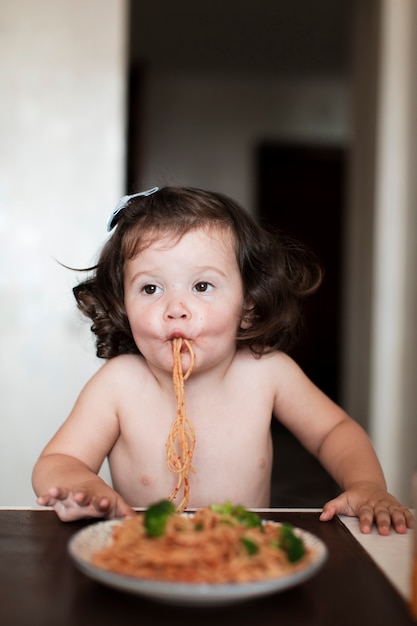 Neonata divertente che mangia spaghetti