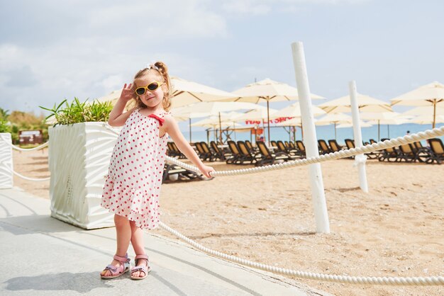 Neonata felice in un vestito sulla spiaggia in riva al mare in estate.