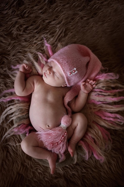 Neonata sveglia del dormiente in berretto rosa su lana