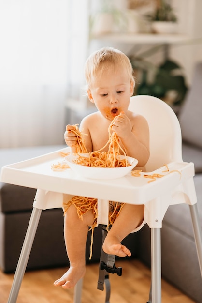 Neonato che mangia pasta nel suo seggiolone