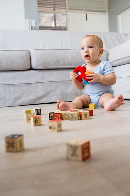 Neonato che si siede sul pavimento e giocare con i giocattoli in salotto
