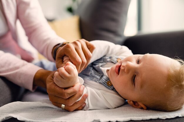 Neonato e sua madre che si tengono per mano mentre fanno esercizi di sviluppo sul divano