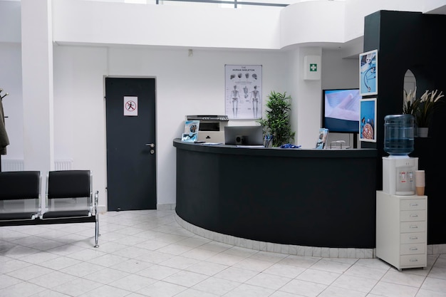 Nessuno in sala d'attesa con reception reception e tv a parete con offerta promozionale in clinica privata. Area di attesa per i pazienti con appuntamenti dal medico nella moderna clinica sanitaria.