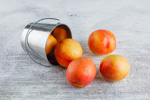 Nettarine sparse da un mini secchio su un tavolo grigio sgangherato. Veduta dall'alto.