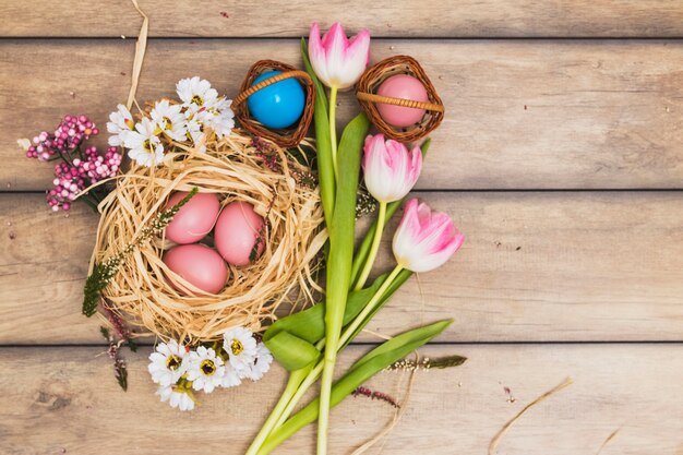 Nido con uova rosa vicino a tulipani