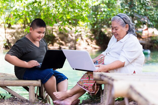 Nipote che insegna al suo computer portatile femminile anziano di uso