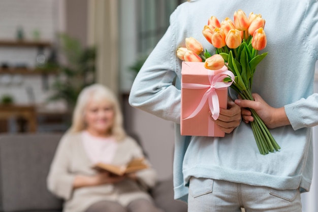 Nipote che nasconde un regalo a sua nonna