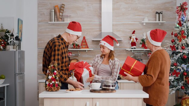 Nipote che porta un regalo di involucro a sorpresa per i nonni che festeggiano il Natale