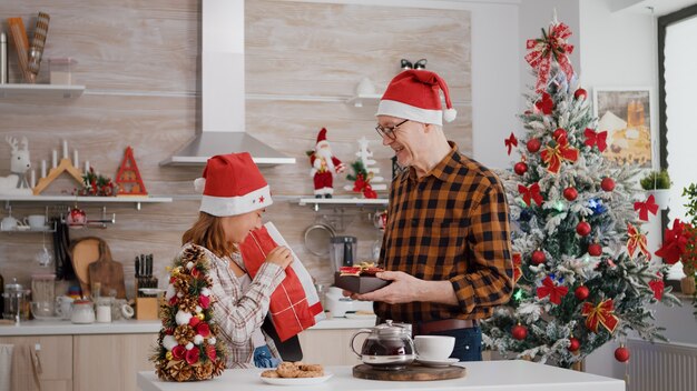 Nipote con il nonno che porta con un regalo regalo di involucro di Natale con un nastro su di esso