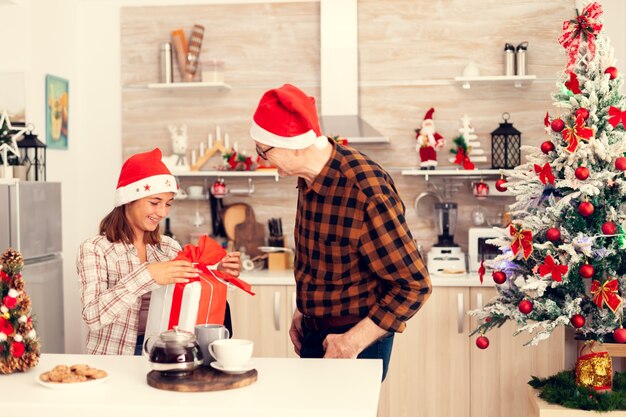 Nipote sorridente che controlla la confezione regalo di Natale con fiocco rosso