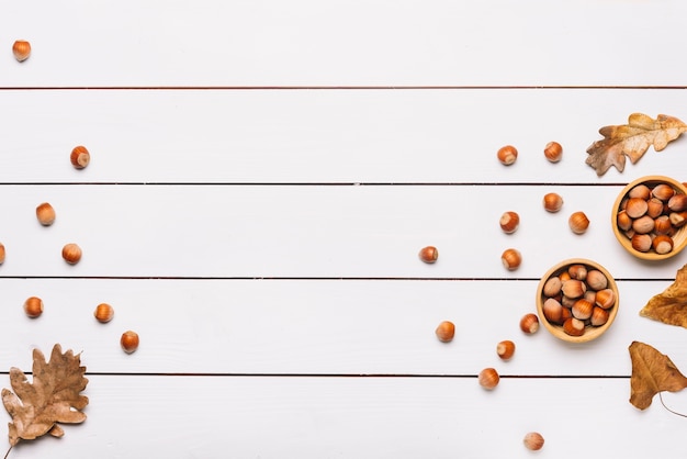 Nocciole e foglie sul tavolo bianco