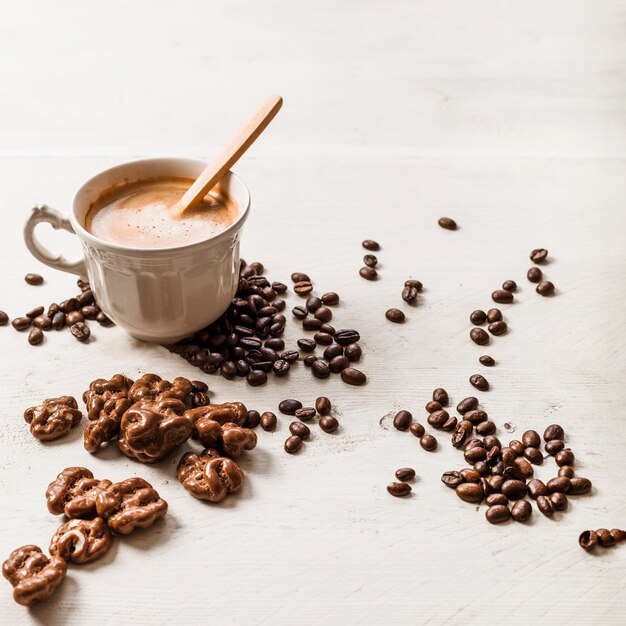 Noce di cioccolato; chicchi di caffè e tazza di caffè arrostiti su fondo di legno