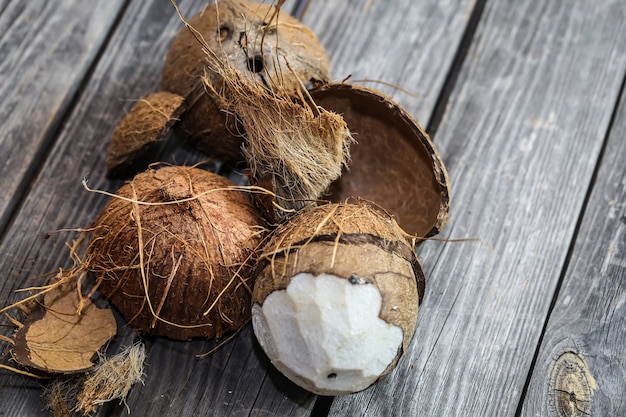 Noci di cocco fresche rotte sulla parete in legno