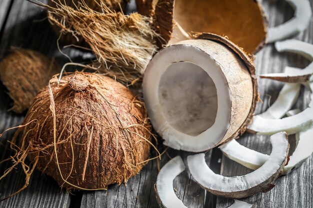 Noci di cocco fresche rotte sulla parete in legno