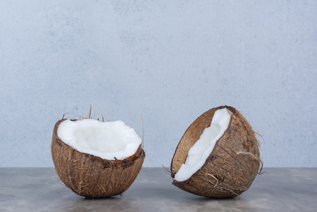 Noci di cocco fresche tagliate a metà sul tavolo di pietra.