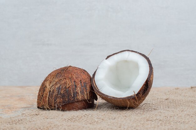 Noci di cocco mature tagliate a metà sul tavolo di marmo con tela.