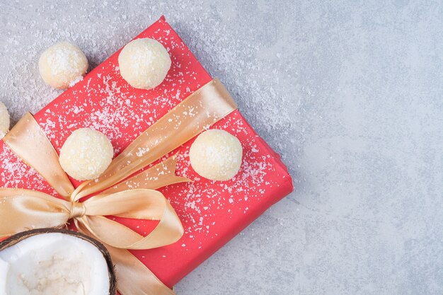 Noci di cocco, pasta frolla e confezione regalo rossa, sullo sfondo di marmo.