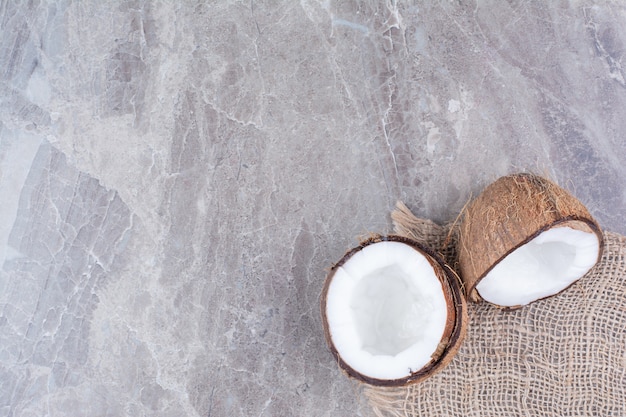 Noci di cocco tagliate a metà con tela sulla superficie della pietra.