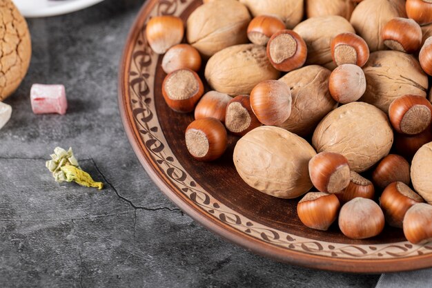 Noci e noci in un piatto decorativo su un pezzo di marmo