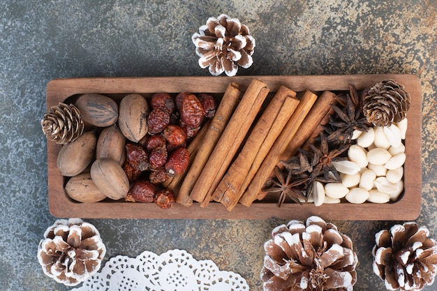 Noci miste con bastoncini di cannella e frutta secca sul piatto di legno. Foto di alta qualità