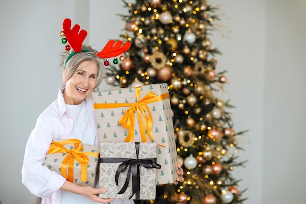 Nonna che indossa il cappello di Natale dei cervi Regali di Natale nelle mani