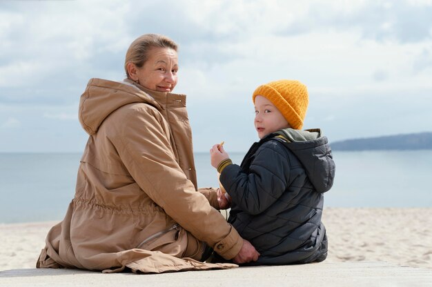 Nonna e bambino del colpo medio in spiaggia