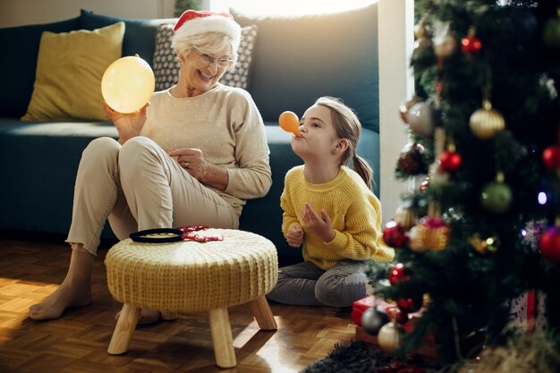 Nonna e nipote felici che giocano con i palloncini mentre festeggiano il Natale a casa