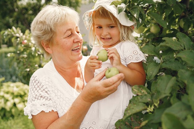 Nonna e nipote insieme, abbracciati e ridenti allegramente in un giardino fiorito di albicocche ad aprile. Stile di vita all'aperto della famiglia.